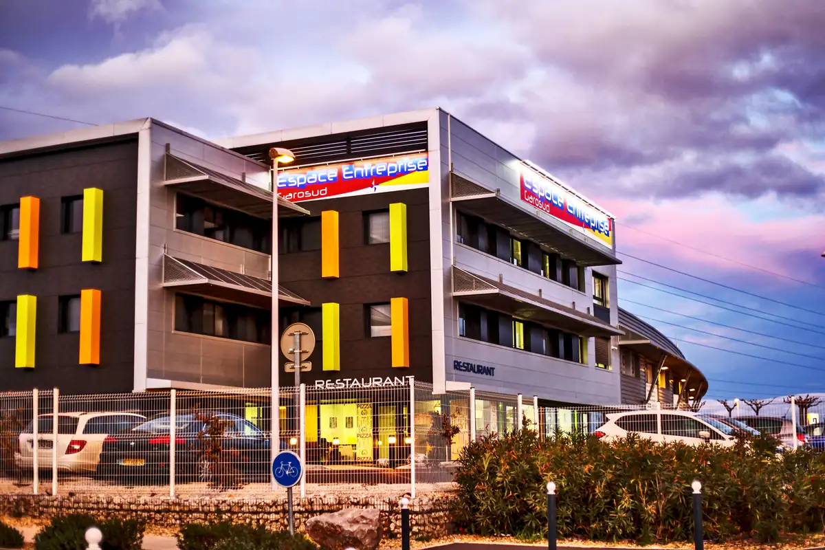 Façade du centre d’affaires Espace Entreprise Garosud au crépuscule, avec le restaurant au rez-de-chaussée